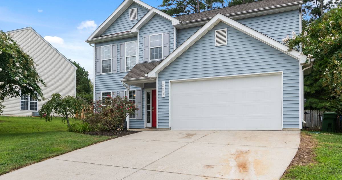 A blue two-story suburban home with a two-car garage and a concrete driveway